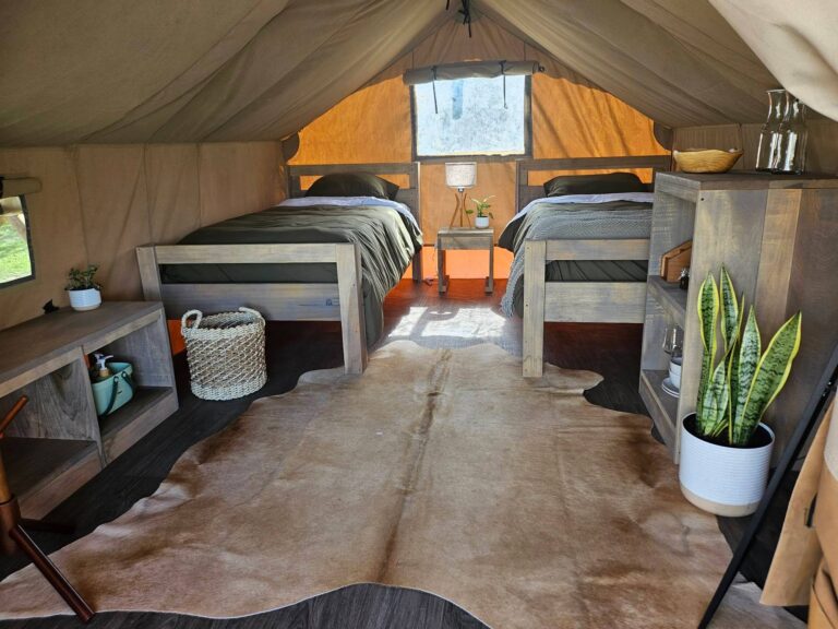 Inside a Rocket Ranch glamping tent with two twin beds and a cowhide rug