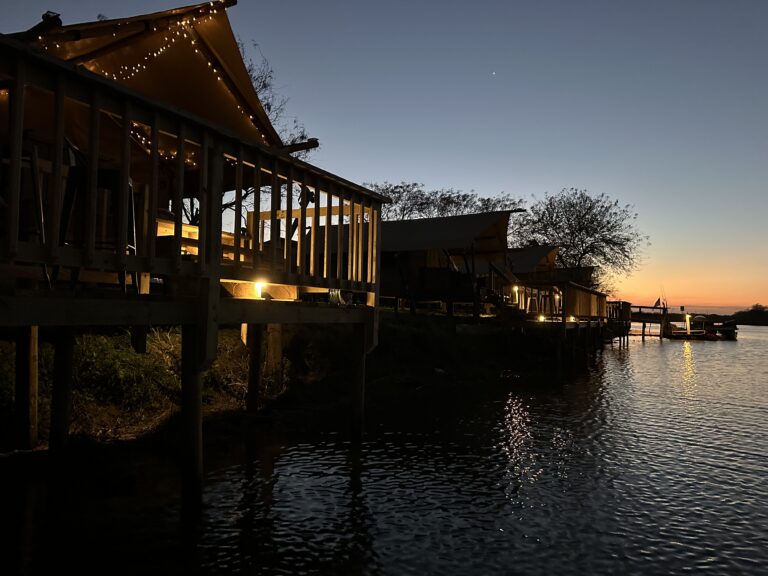 Covered riverside decks with string lights at dusk on the Rio Grande