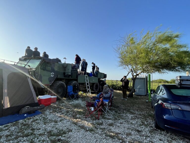 Guests standing on top of a military truck at the Rocket Ranch Outpost, with a tent and camp chairs set up nearby