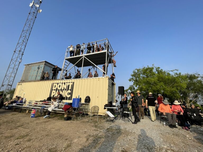 Guests filling the viewing tower and bleacher seating at the Rocket Ranch Outpost on a hazy morning