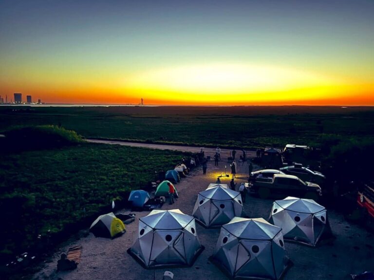 Dome glamping tents at Rocket Ranch at sunset with the SpaceX Starbase launch site on the horizon